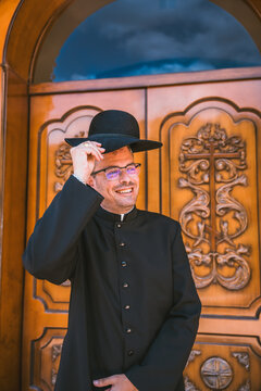Smiling Catholic priest adjusting his hat in Altea, Spain