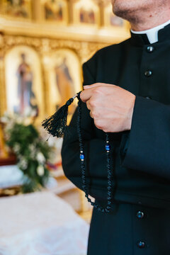 Close-up of a priest holding rosary beads in a church
