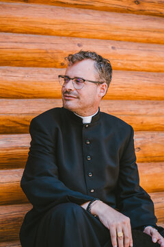Catholic priest seated outside on wooden background