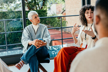 Mature woman with grey hair attentively listening during a business presentation discussion