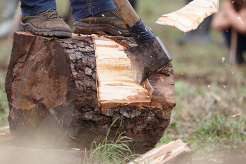 A man cuts a log of wood with an axe in a rural sports competition
