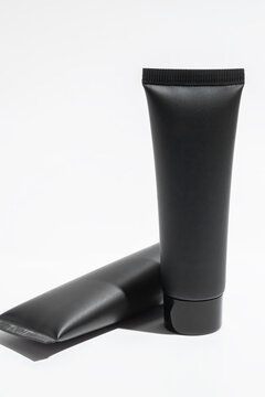 Black cosmetic tubes on a white background