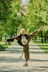 Person executing high kick balancing on one leg in serene urban park with green trees in background...