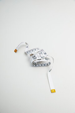 Top view of a curled white measuring tape on a plain background
