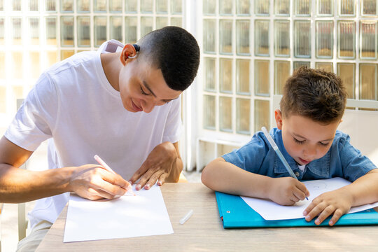 Young man with disabilities mentoring a young boy in drawing