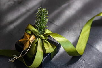 Elegant Christmas gift with green ribbon in dramatic lighting