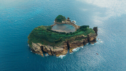 Aerial view of a lush green islet with a historic building in the Azores