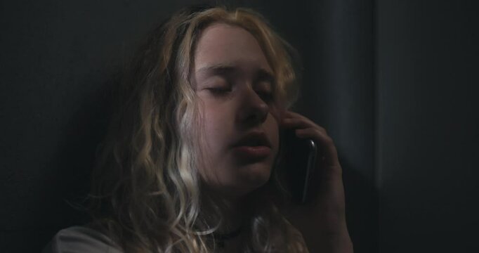 Sad blonde girl talking on the phone after a shower late at night. Communication instead of sleep with loved ones at night