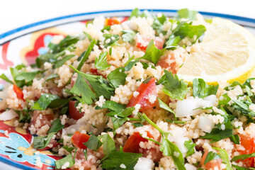 Tabbouleh salad with couscous and vegetables isolated on white background. Close up