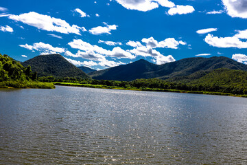 Background of high angle view from the top of the mountain where you can see the grassland, rice fields, large reservoir and clear sky during the adventure travel.