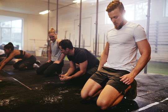 A group of diverse friends take a break after a crossfit class in their gym. A fit young man looking tired after a workout session