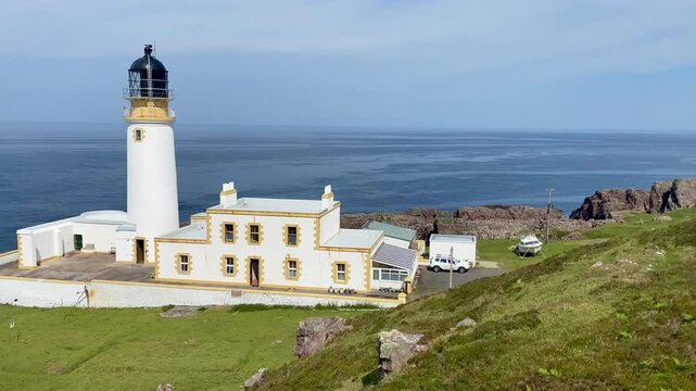 Pan across headland and lighthouse overlooking ocean to distant islands