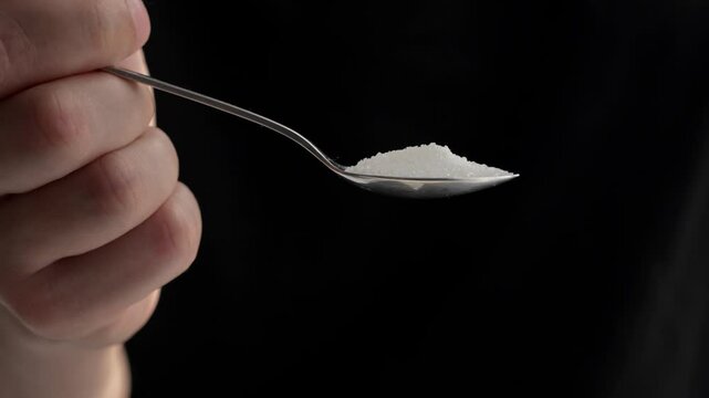 sugar in a teaspoon on a black background.
The harm of sugar.
Granulated sugar with a slide in a spoon.
Tea, sugar, sweet, product, ingredient