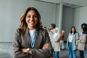 Happy businesswoman smiling at conference with diverse group of professionals in the background