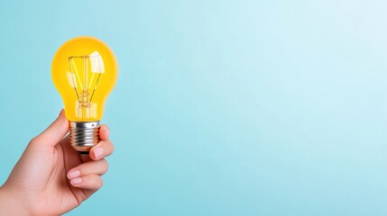 Hand holding light bulb on pastel blue background, idea concept with copy space for your text or design