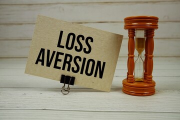 Loss Aversion text on paper card with Hourglass on