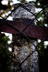 Color vertical photo of a concrete pillar with a metal rusty horizontal crossbar and a metal mesh...
