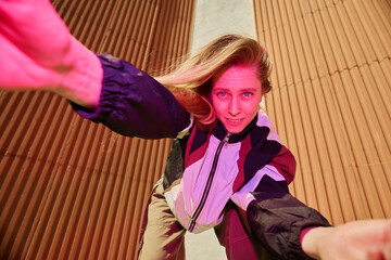 Portrait of young Caucasian woman taking selfie while leaning forward energetically and smiling...