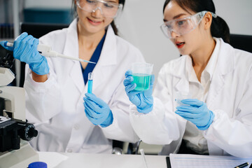 Fototapeta premium Young scientists conducting research investigations in a medical laboratory, a researcher in the foreground is using a microscope