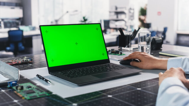 Anonymous Engineer Working in the Lab on a Laptop Computer with Mock Up Green Screen Chromakey Display with Motion Tracker Placeholders. Photo Template for Industrial Content Creation and Presentation