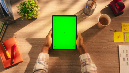 Anonymous Office Worker Using Tablet Computer with Green Screen Mock Up Display for Social Media Posting. Man's Hands Holding a Device with Isolated Area for App, Software, Website Promotions