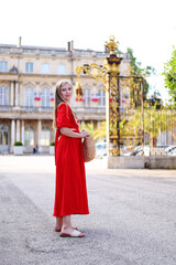 woman in a red dress walks in the center of Nancy.