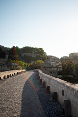 Pont Vieux de Béziers au lever du soleil en août, vue vers le centre historique baigné dans une lumière douce du matin.