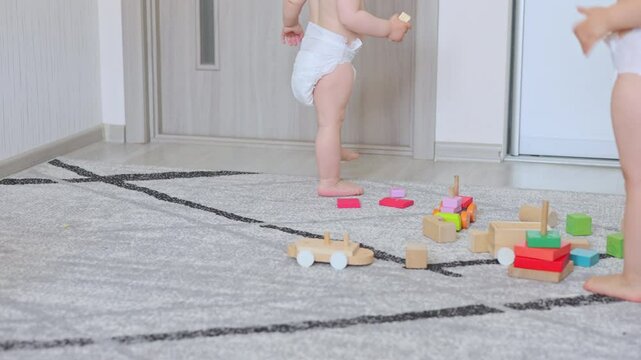 baby boy and kid in diaper walking in room,playing with wooden blocks,chewing some snack.portrait of siblings or friend.infant toddler stepping on weight scale.smiling child, close up,portrait.