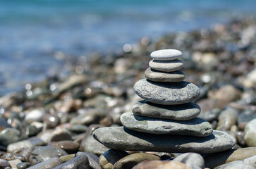 Balanced pebble pyramid silhouette on the beach with the sea