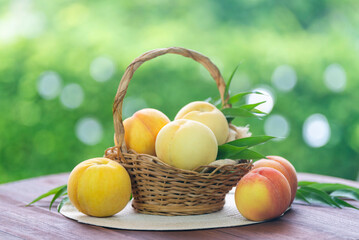 Fresh three kinds of peaches on blurred greenery background, Three colored peaches in basket on wooden table in garden.