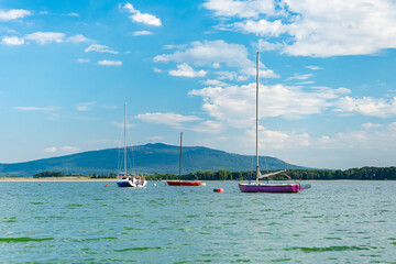 Fototapeta premium Zalew Mietkowski, mountain landscape with a view of Mount Sobotka, sailboats moored at the shore. A popular place for summer recreation and water sports.