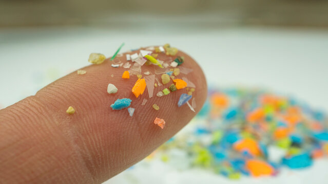 Macro shot of microplastics on a human finger. Concept of plastic pollution with nanoplastics. Soft focus on micro plastic particles that cannot be recycled with copy space on the right.