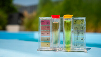 A pool water testing kit with pH and chlorine levels displayed in tubes, set against a blurred...