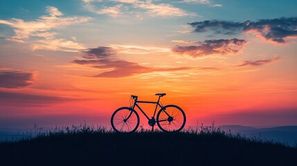Obraz premium A bicycle silhouetted against a stunning sunset landscape, with the sky ablaze in warm colors and the horizon stretching into the distance.