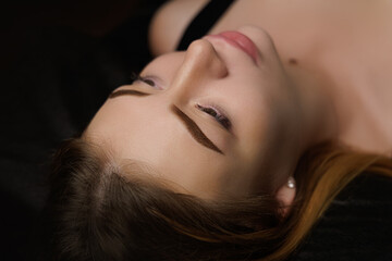 Obraz premium Beautiful eyebrows after permanent eyebrow makeup girl lying dark cosmetology salon Permanent eyebrow makeup, eyebrow tattooing with brown pigment for PMU.