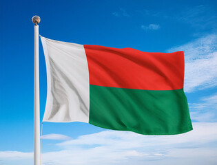 The flag of Madagascar fluttering in the wind with blue sky background