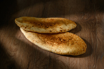 Freshly baked pita bread or flatbread on wooden background.