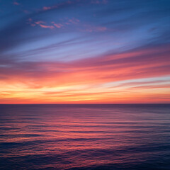 Fototapeta premium A sunset over a calm ocean with vibrant orange and pink hues.