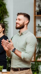 Fototapeta premium smiling man with beard applauding at business meeting with plants in background.