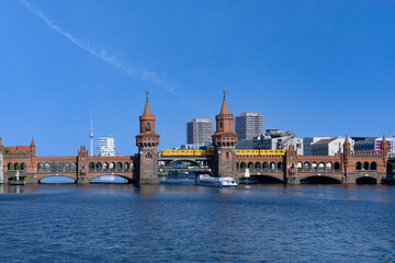 Fototapeta premium Yellow S-Bahn crossing the Double deck Oberbaum bridge over the Spree river, Berlin, Germany