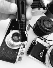 Photographer repairing old camera on white background.