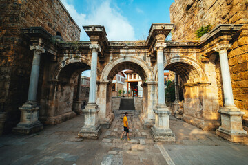 Obraz premium Hadrian's Gate. Young tourist in yellow t-shirt examines the gates. Photo taken on a cloudy day. Turkey.
