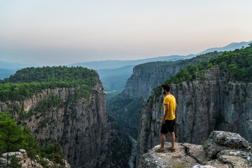 Naklejka premium A man climbs Tazi Canyon and enjoys the magnificent harmony of the trees and mountains in the canyon. Manavgat, Turkey.