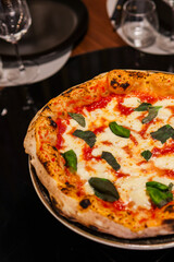 Pizza margherita tradizionale napoletana con sugo di pomodoro, mozzarella e basilico fresco servita in una pizzeria elegante