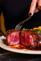 Filetto di manzo con cottura al sangue servito in un ristorante elegante con la riduzione della sua salsa, insalata verde e insalata di cavolo come contorno