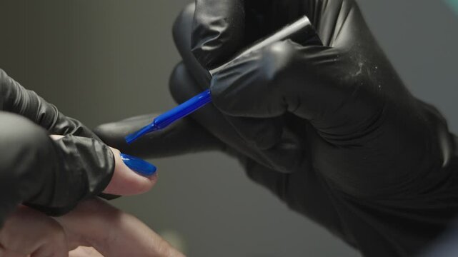 Woman manicure master makes gel coating varnish in the salon. The concept of beauty professional nail care