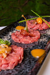 Tartare di carne decorata con olive, capperi e pomodori servita come antipasto in una braceria elegante