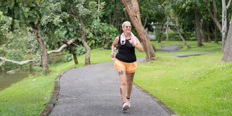 Energetic Older Woman Running in Scenic Park Pathway