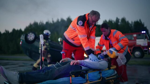 Female and Male Paramedic Rescue Team Saving Life of a Young Male Involved in a Traffic Accident. Doctors Performing Emergency CPR, Compressing His Chest and Providing Artificial Ventilation