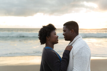 Smiling young African couple looking into each other's eyes on a beach